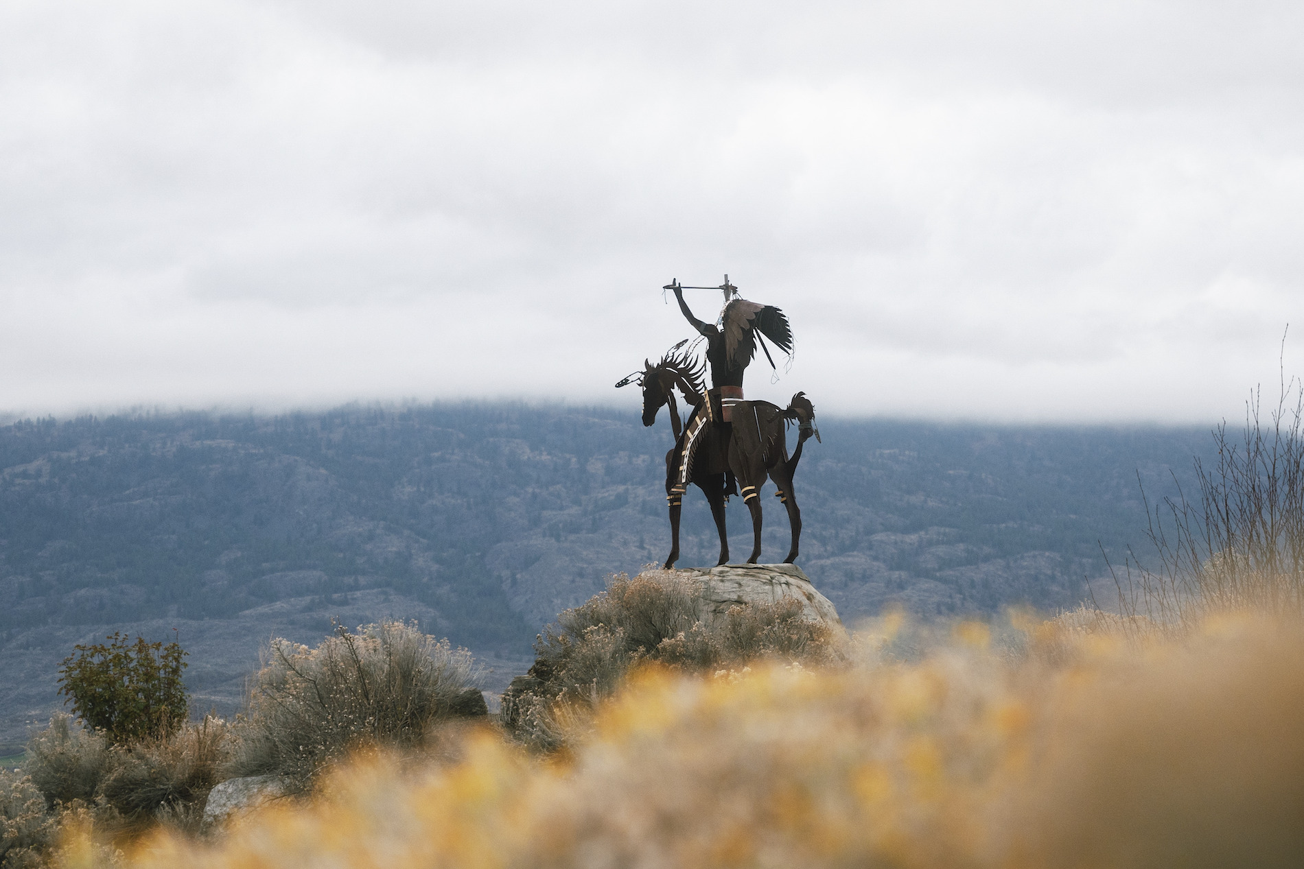 An Indigenous horserider statue overlooks the Okanagan landsdcapes.