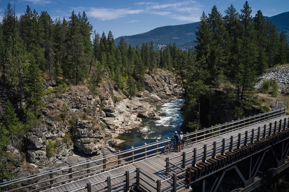 People looking at a river while taking a rest on their bikes