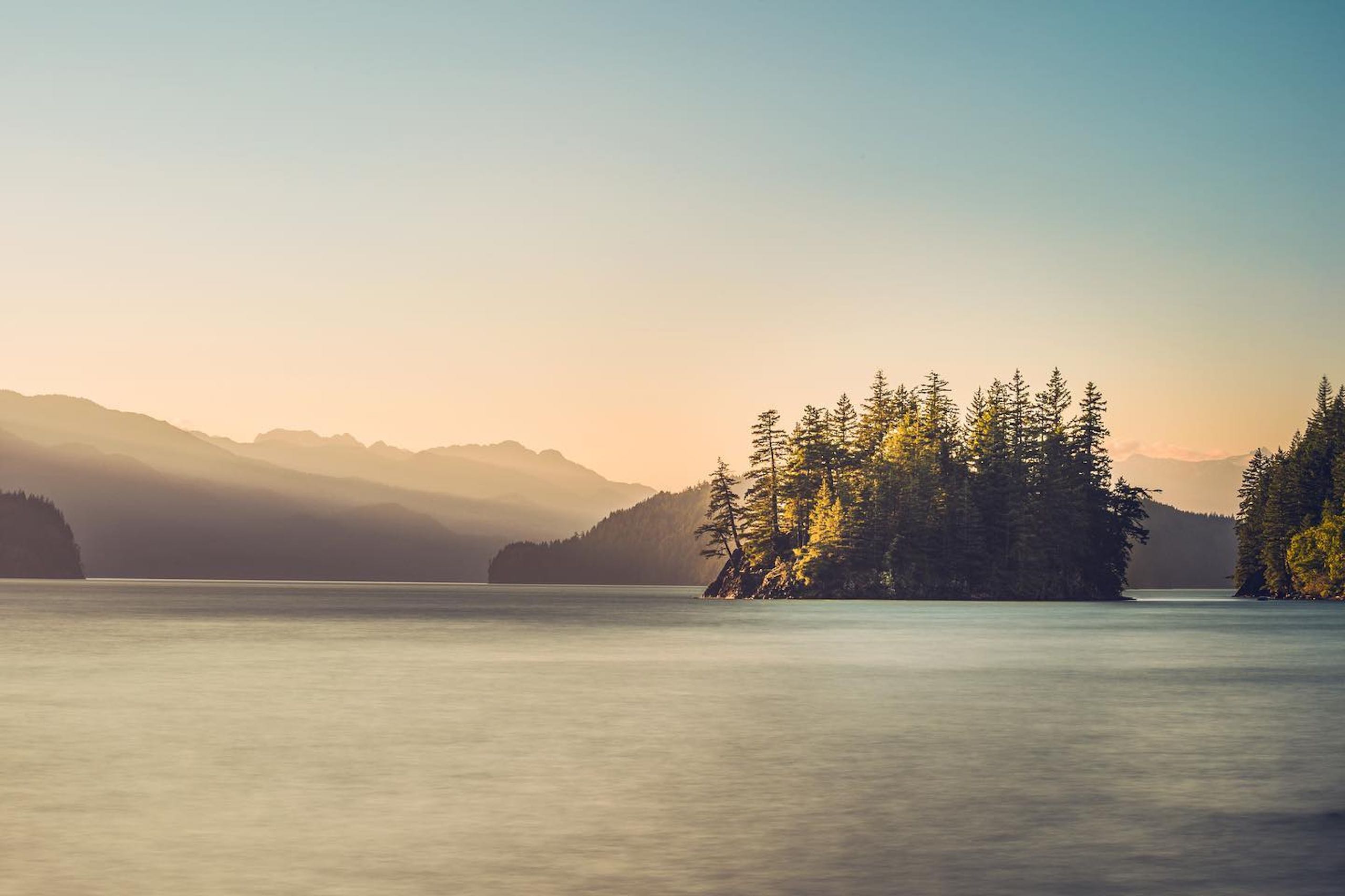 Small island in the middle of a body of water and a mountain range in the background