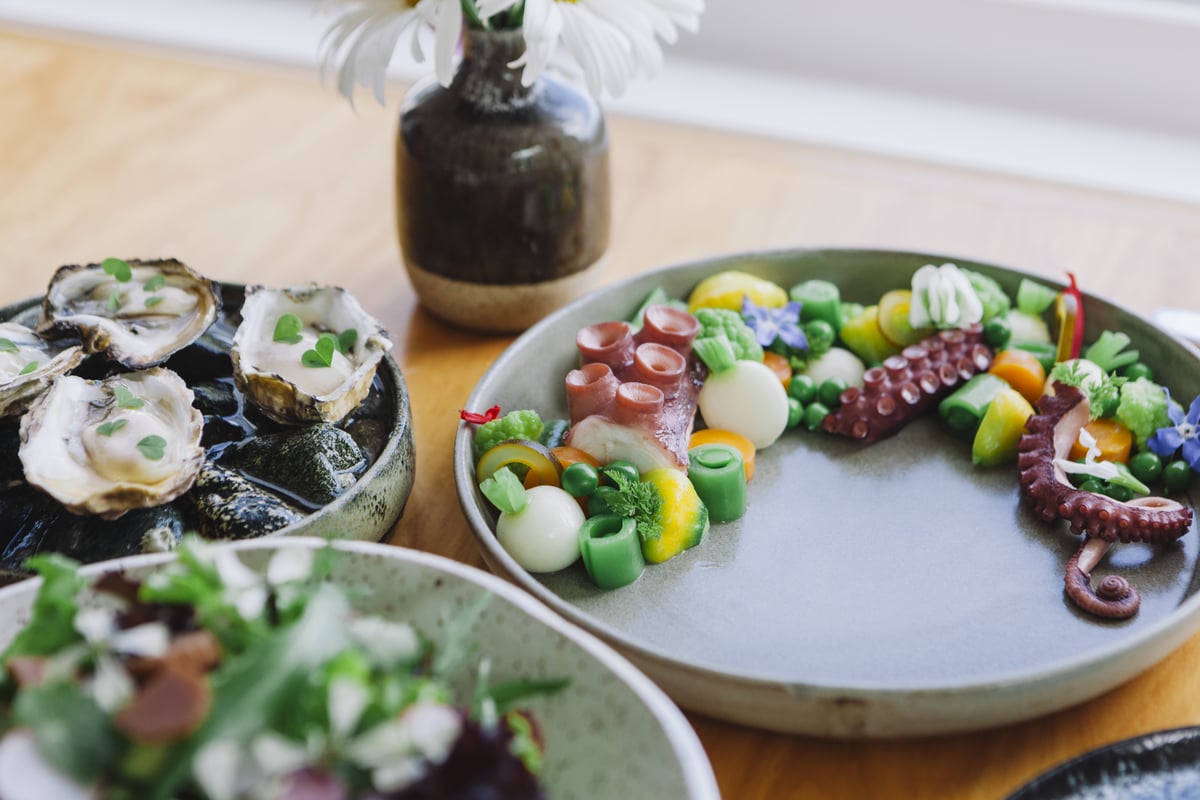 Three dishes of seafood on a wooden table with an assortment of sushi and other items.