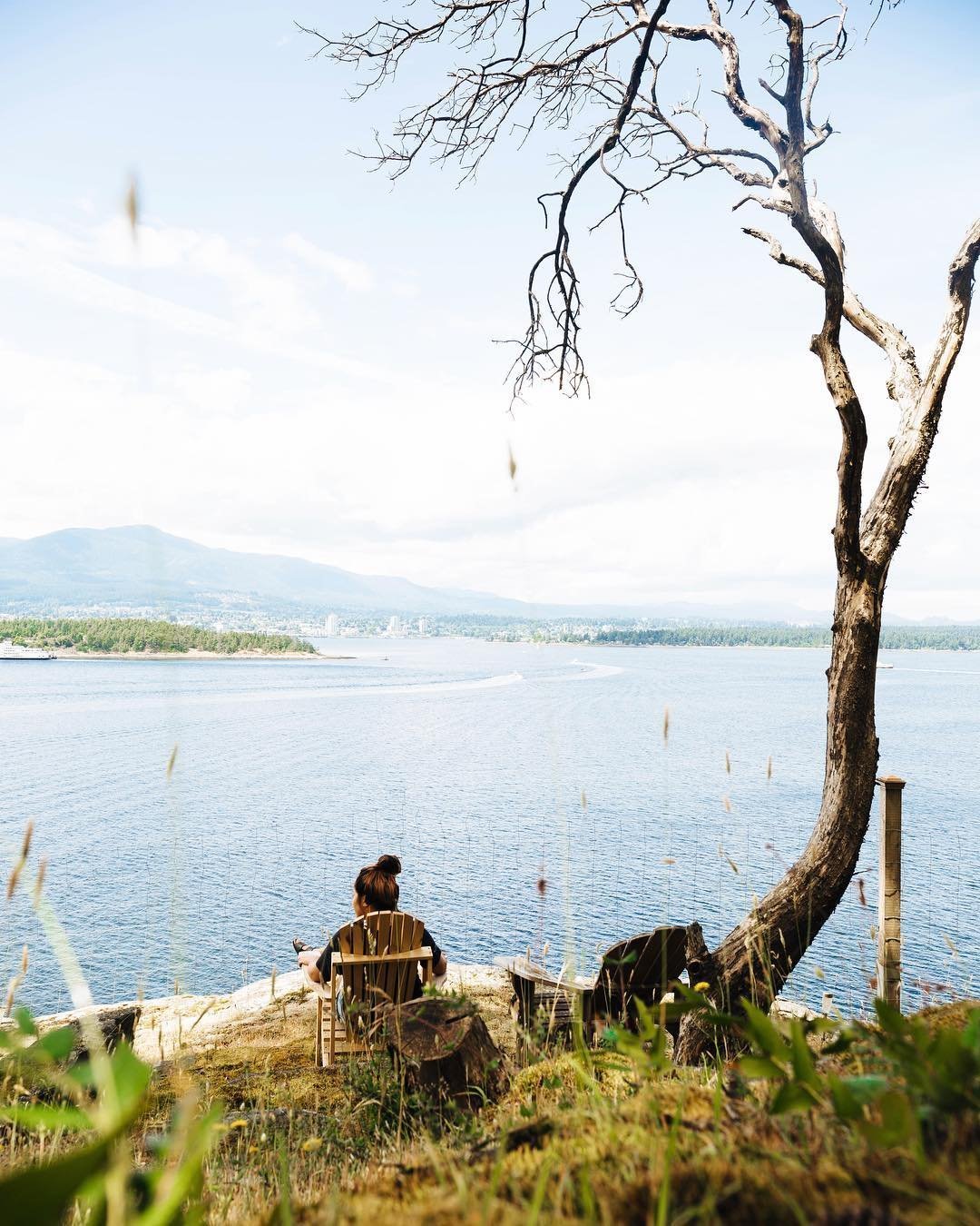 A person sits in a chair on a rocky ledge looking out at the water on Gabriola Island.