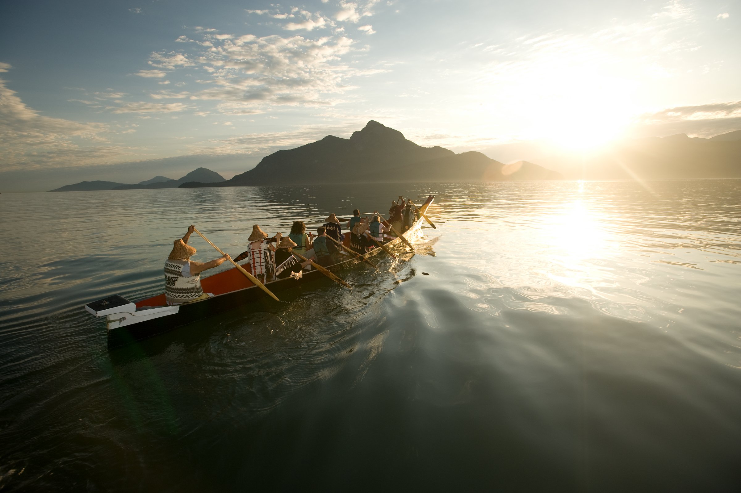 A group with Takaya Tours, rowing a traditional First Nations canoe in Howe Sound with mountains in the background.
