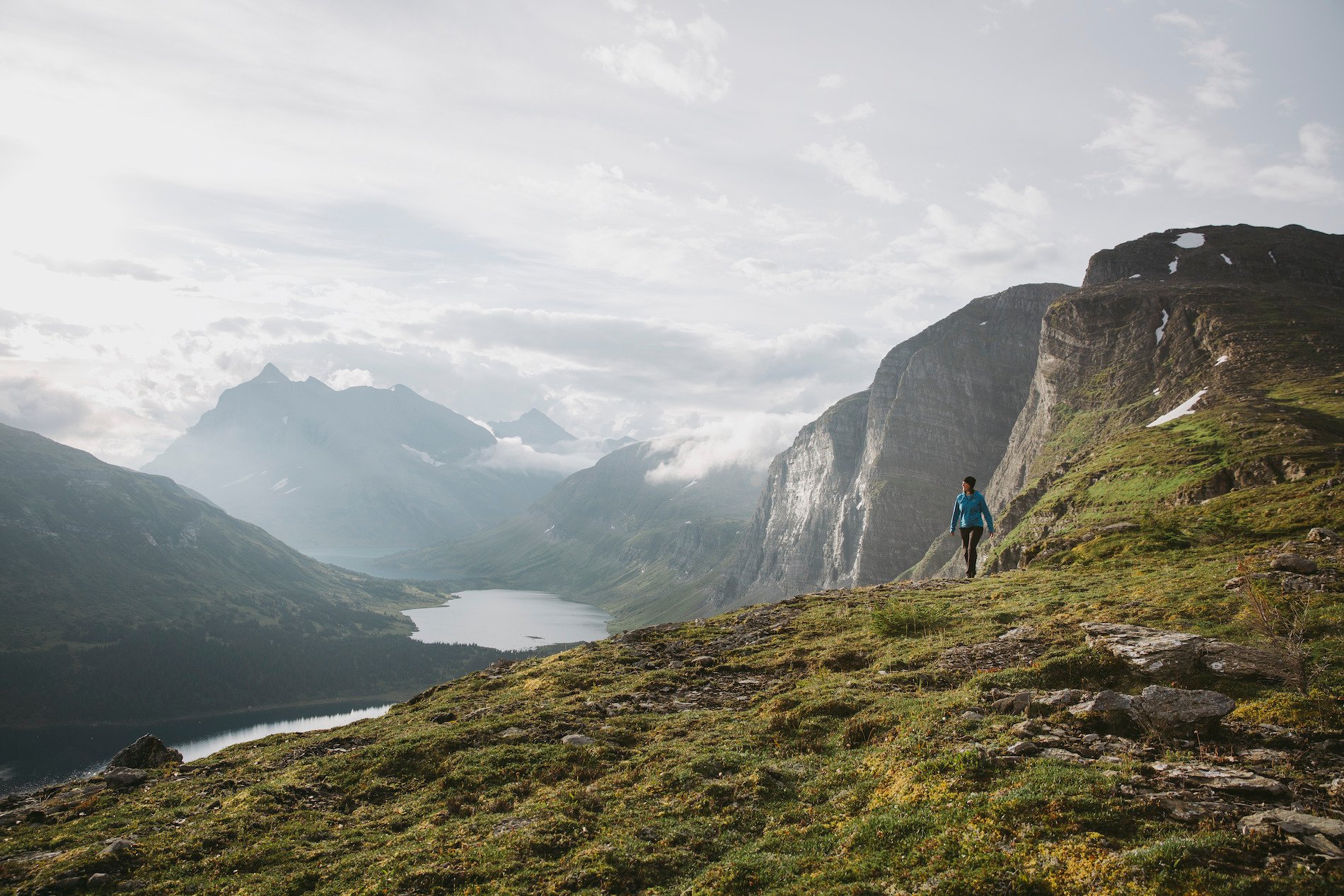 A hiker surrounded by towering mountains and alpine lakes.