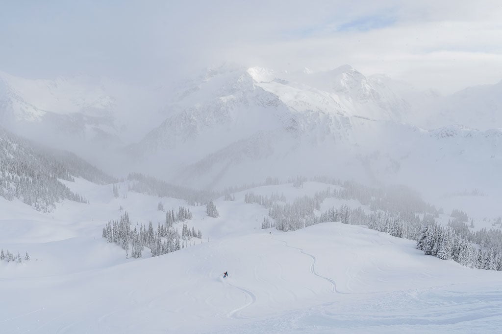 人们在 Selkirk Tangiers 直升机滑雪中从山坡滑下