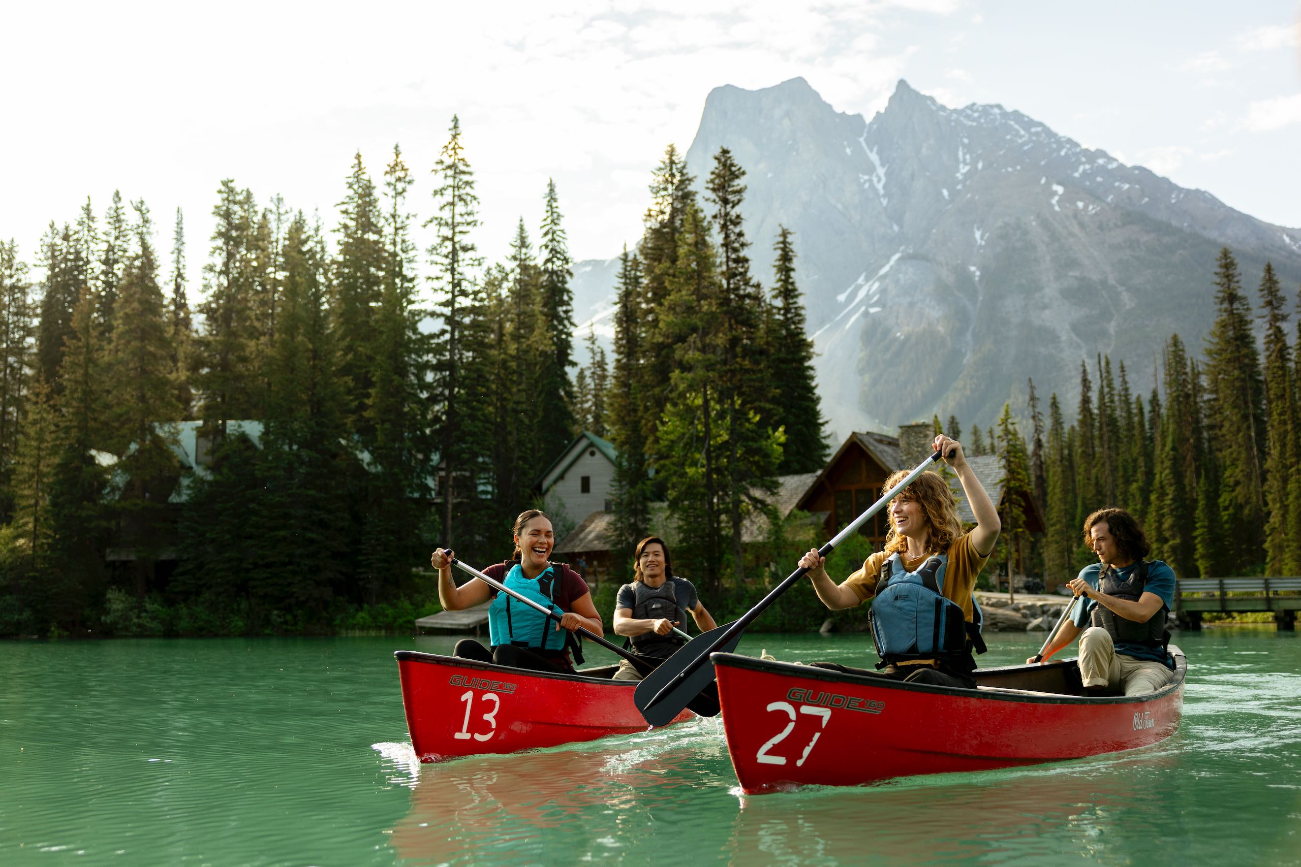 Four friends canoeing on the turquoise waters of Emerald Lake in Yoho National Park in the Canadian Rockies, with Emerald Lake Lodge in the background.