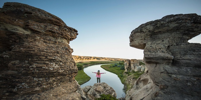 A person standing between two stone structures at Writing-On-Stone Provincial Park