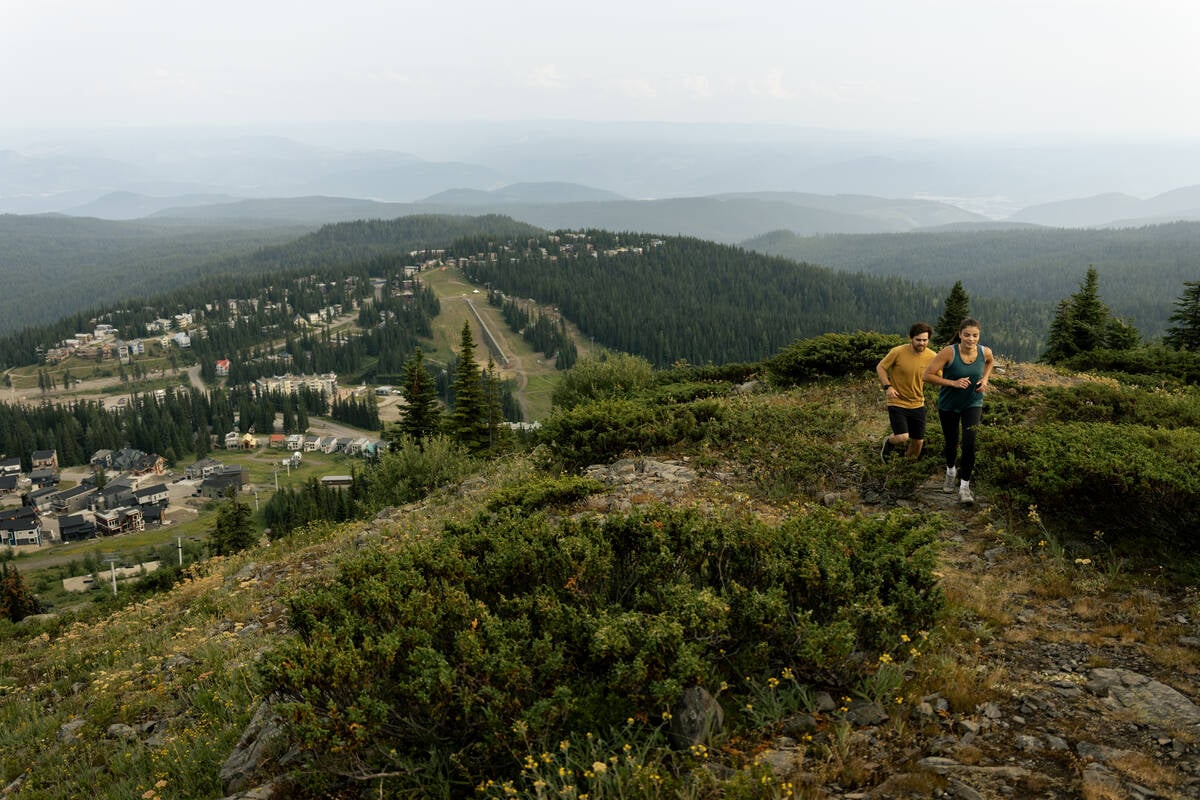 People trail running up SilverStar Mountain, with SilverStar Mountain Resort village in the background