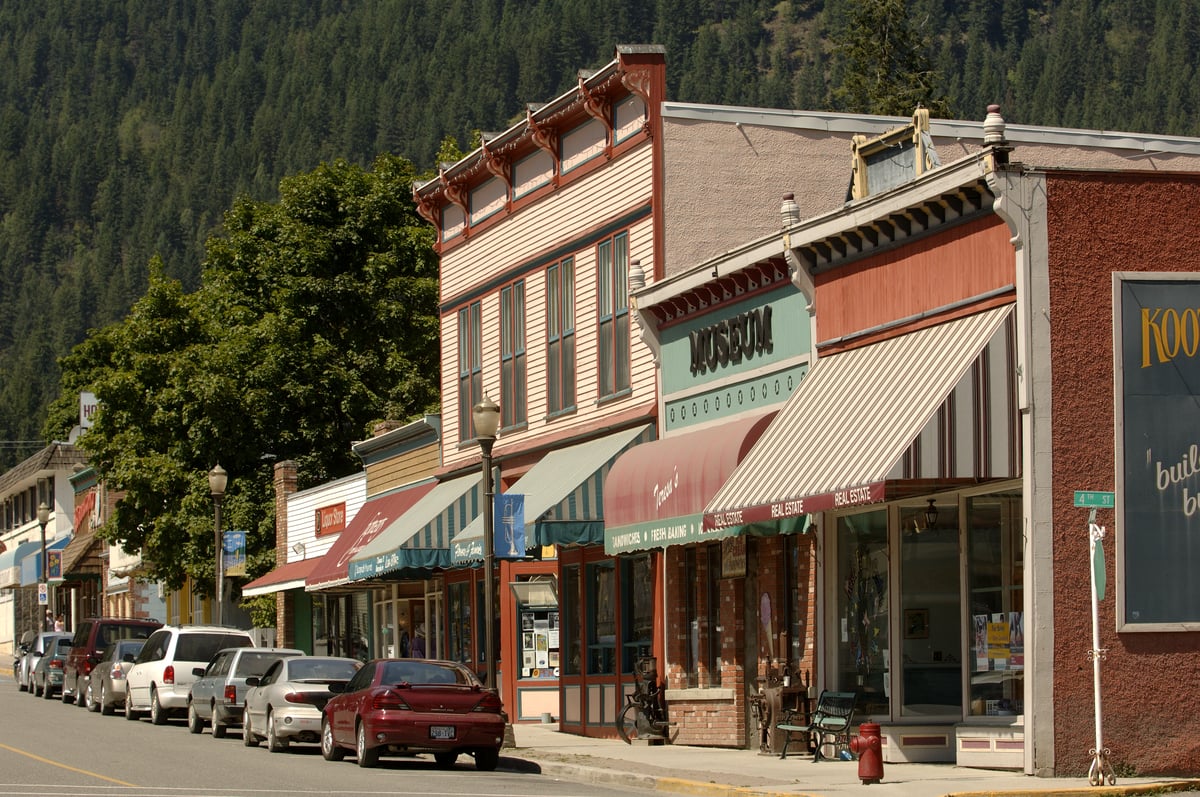 Storefronts in downtown Kaslo during the daytime. Cars are parked out front on the road.
