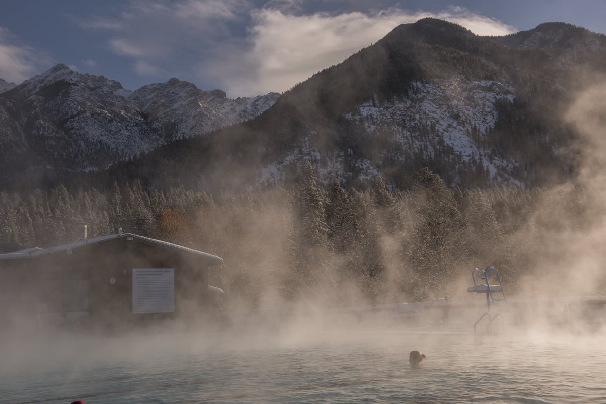 A person sits in the Hot Springs with steam coming off the pool