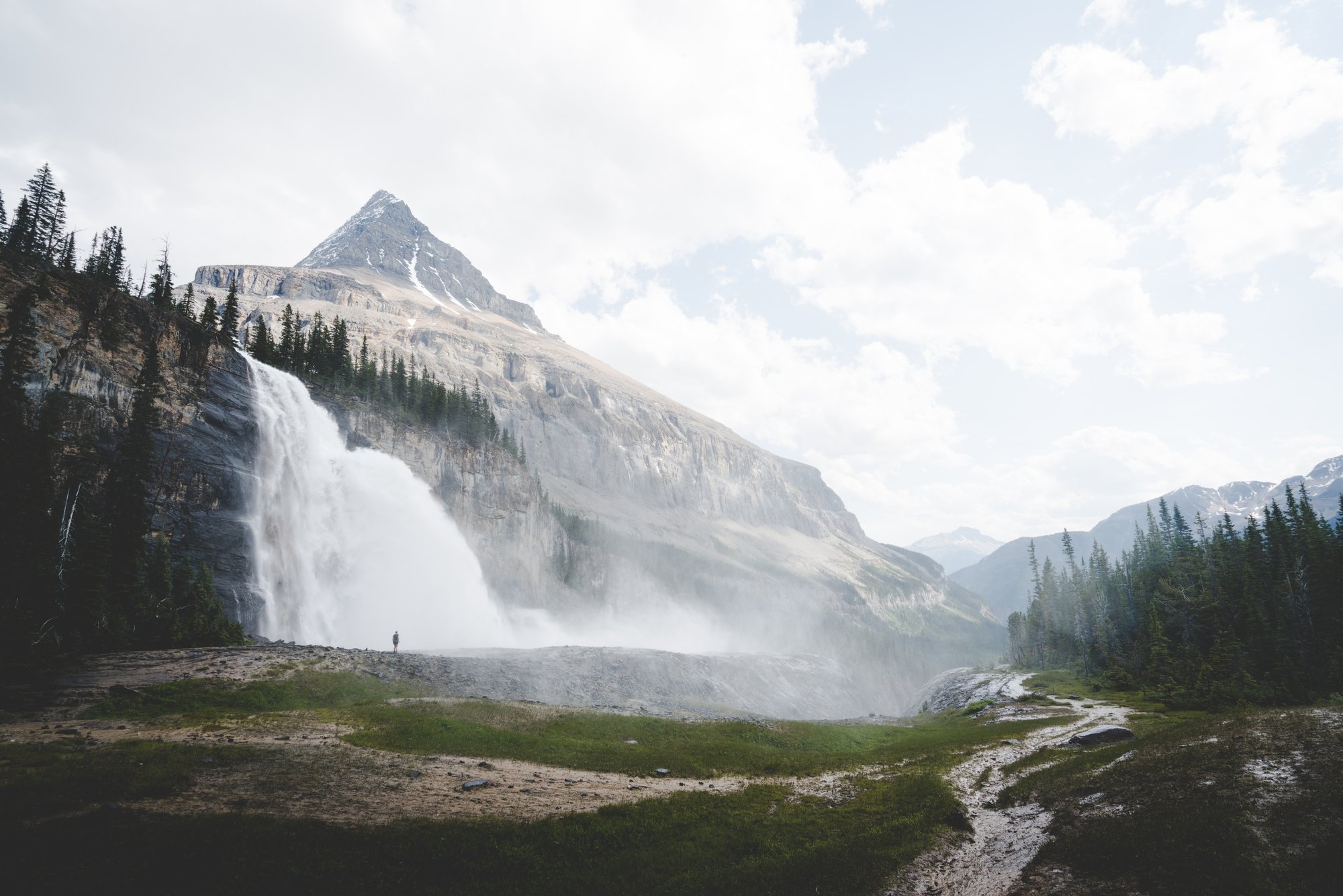 A figure is shown is hiking at Emperor Falls on the Berg Lake Trail in Mount Robson Provincial Park near Invermere, with cascading water in the background.