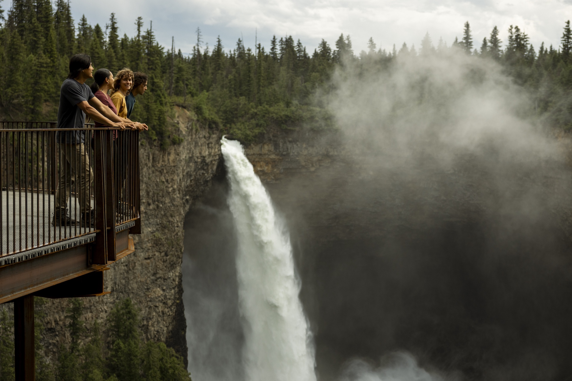 一群朋友在威尔斯格雷省立公园的观景平台上欣赏 Helmcken Falls 的景色。这里距离停车场仅需短程步行即可抵达，而 Helmcken Falls 也是加拿大第四高的瀑布。
