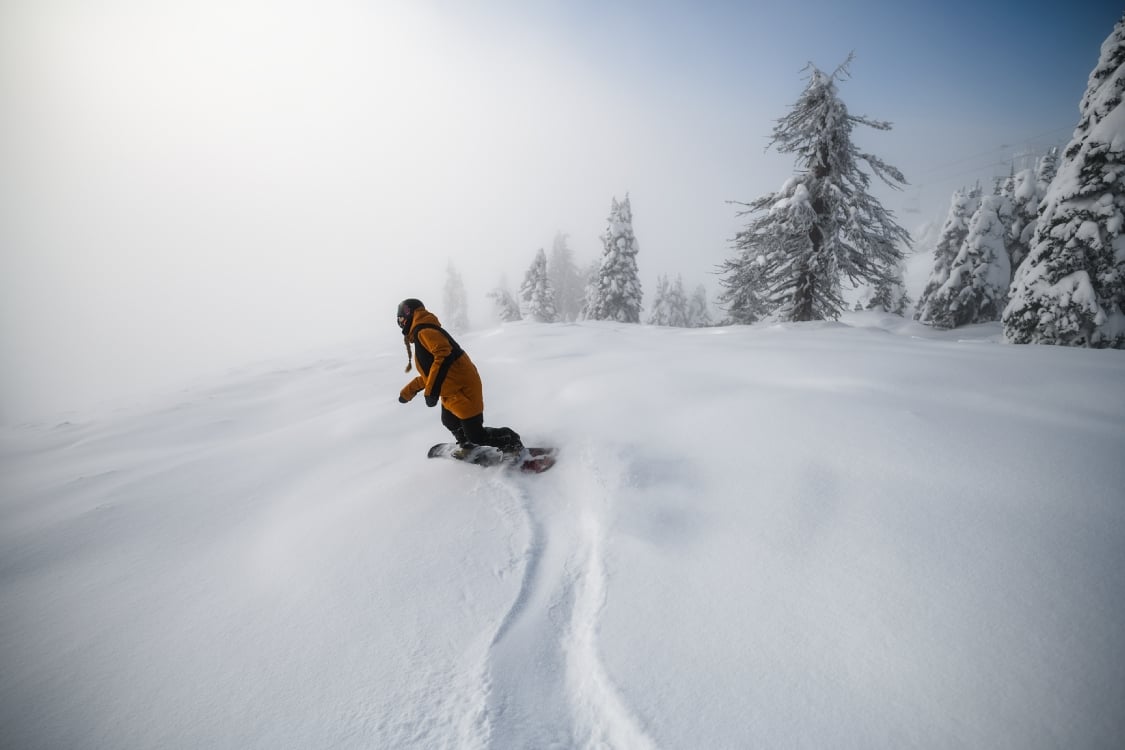 A snowboarder snakes off into the mist on a powder day at Big White Ski Resort, Andrew Strain